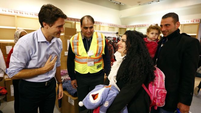 Justin Trudeau greets a family of refugees from Syria as they arrive at Pearson International airport, in Toronto, on Friday, Dec. 11, 2015. (Nathan Denette/CP)