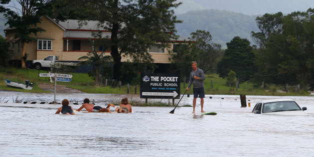 Local residents paddle down the main street on Friday in Billinudgel.